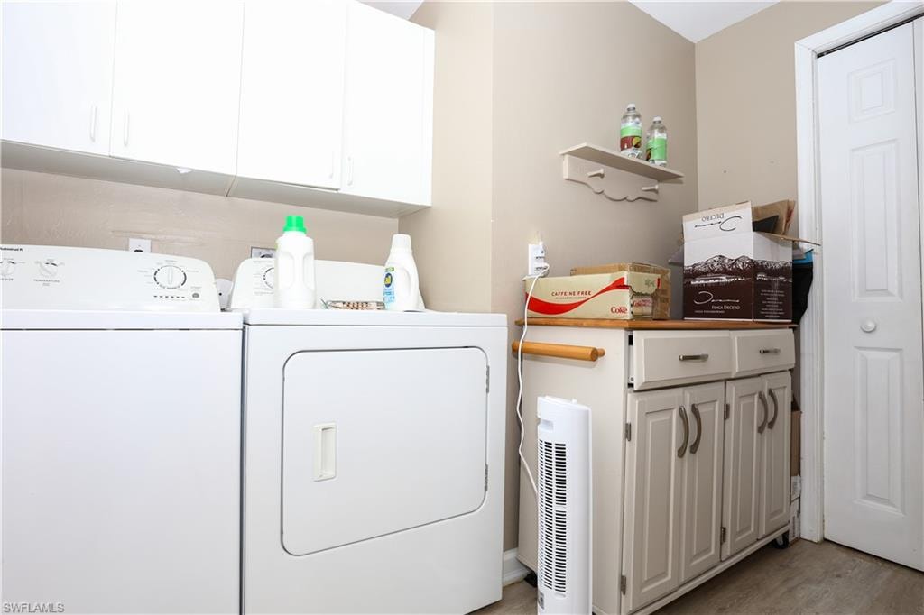 Laundry room with cabinet space, washing machine and clothes dryer, and light wood-type flooring