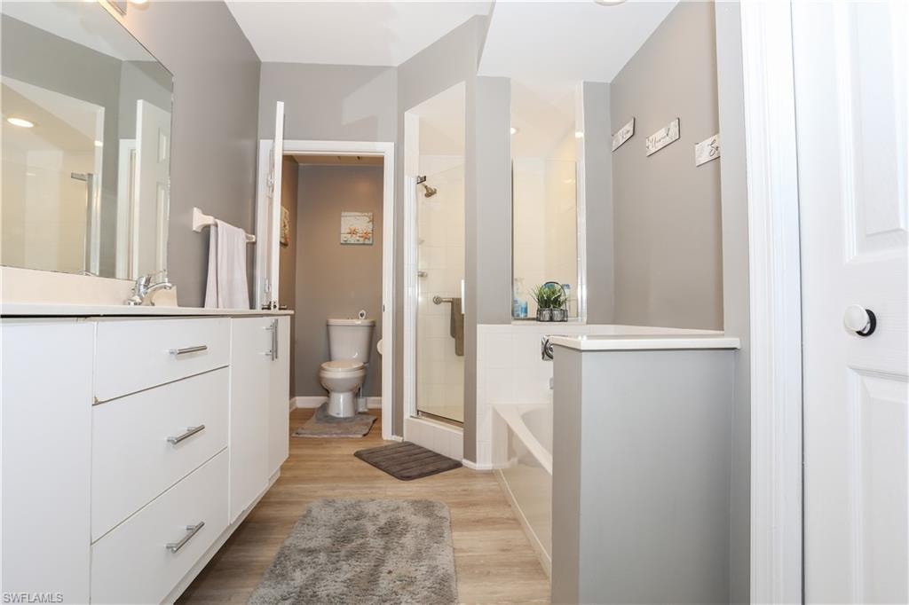 Bathroom with a shower stall, a bath, light wood-style floors, and vanity