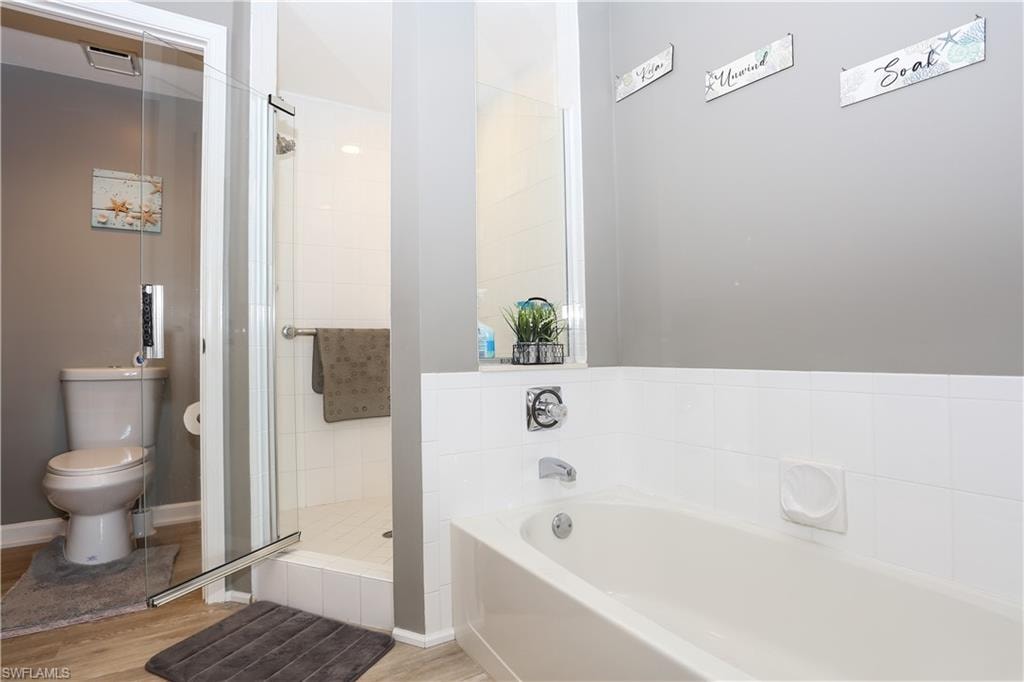 Full bath featuring a shower stall, a garden tub, and light wood finished floors