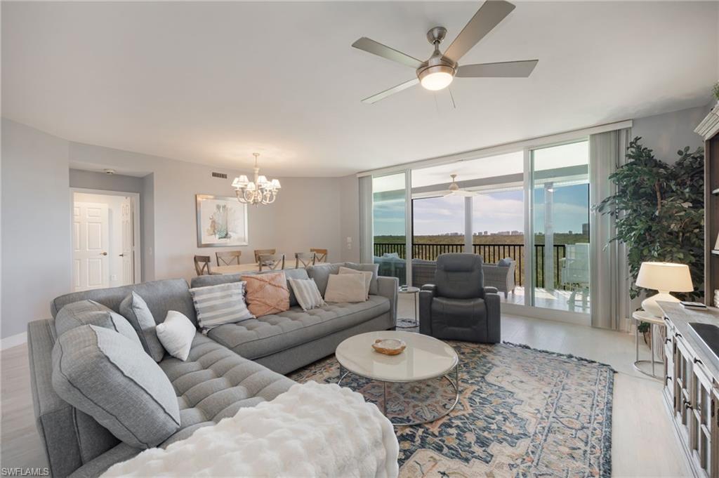 Living area with wood finished floors, a ceiling fan, suspended lighting, and expansive windows