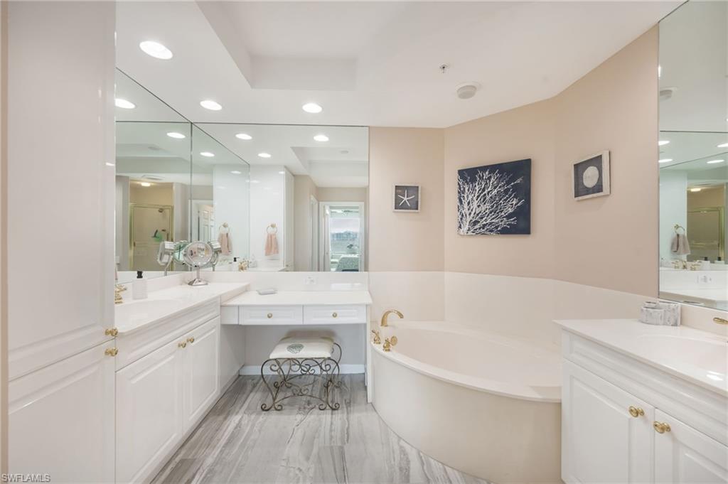 Bathroom featuring two vanities, recessed lighting, and a garden tub