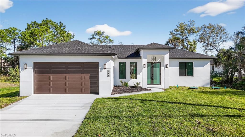 View of front of home featuring stucco siding, an attached garage, concrete driveway, a front yard, and roof with shingles