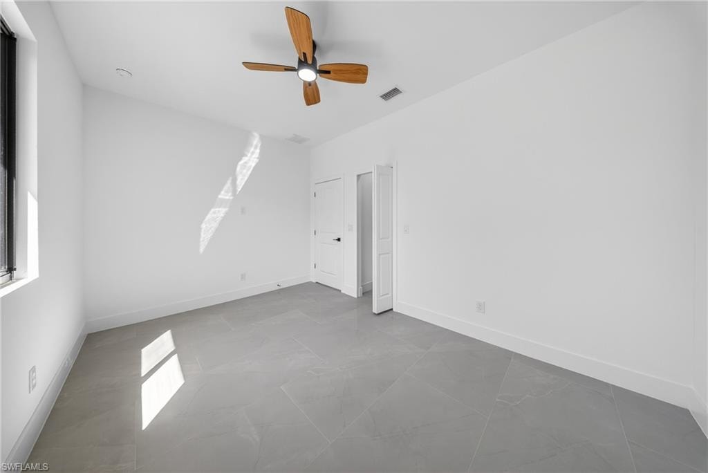 Unfurnished bedroom with a ceiling fan and multiple windows