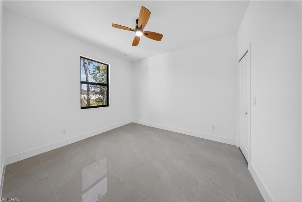 Empty room featuring baseboards and ceiling fan