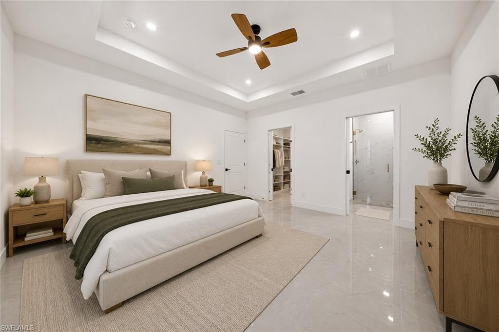 Spacious room featuring a tray ceiling with recessed lighting and a ceiling fan
