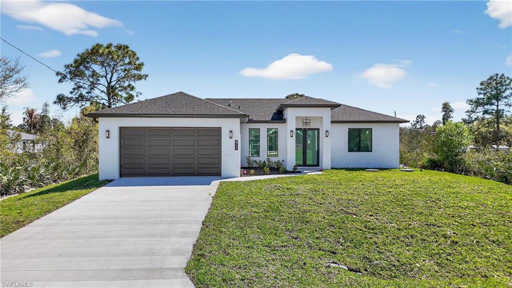 View of front of house with concrete driveway, stucco siding, and a front lawn