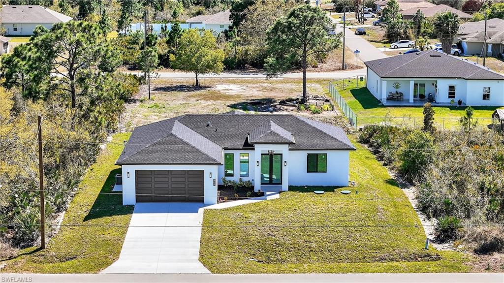 View of front of home featuring a shingled roof, stucco siding, concrete driveway, an attached garage, and a residential view