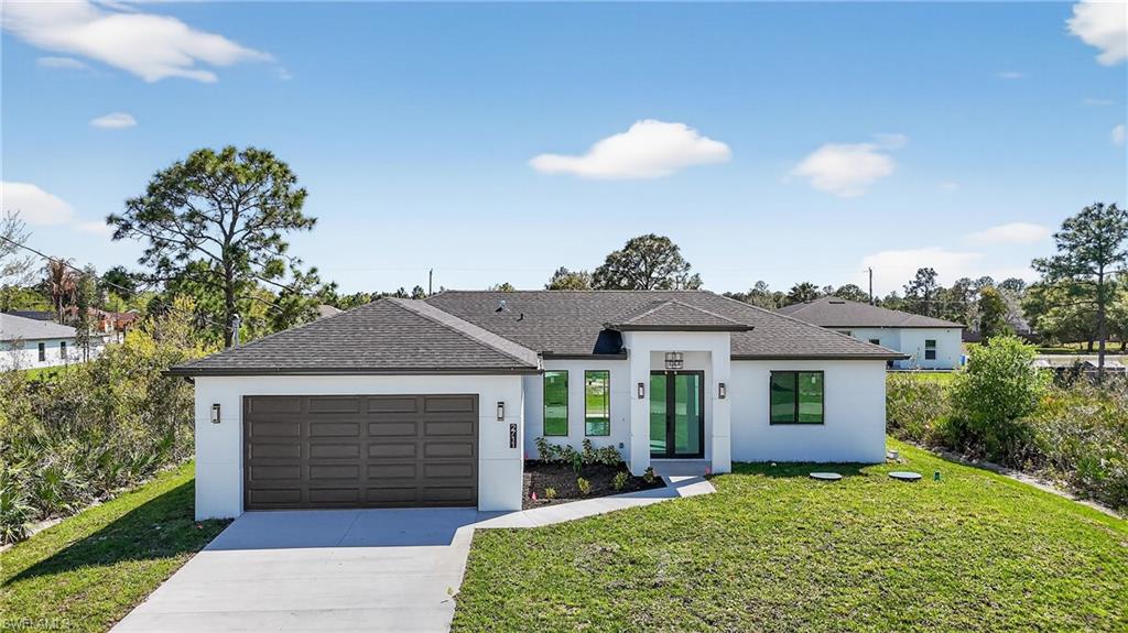 View of front facade featuring driveway, a front lawn, stucco siding, and a garage