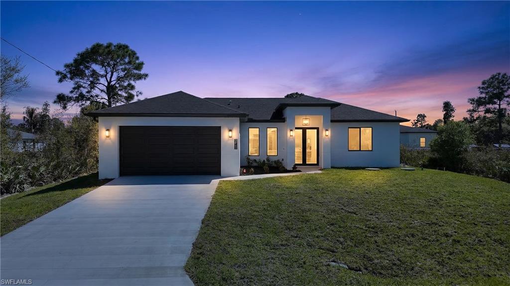 View of front of house featuring a front lawn, stucco siding, driveway, a garage, and roof with shingles