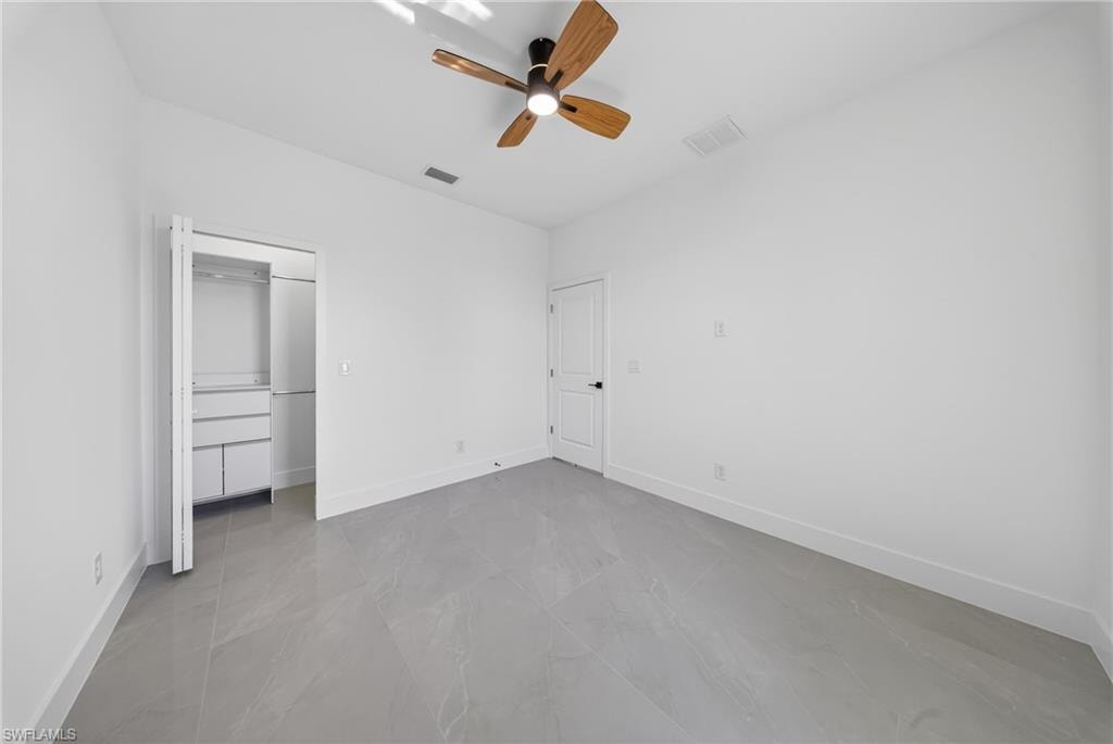 Unfurnished bedroom with a ceiling fan, a spacious closet, and lofted ceiling