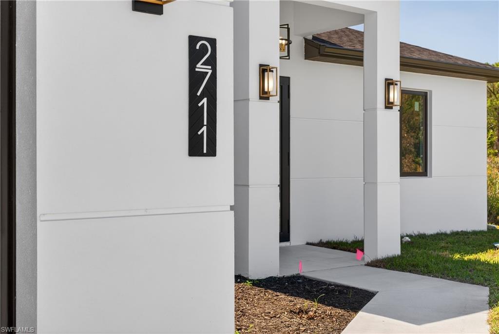 Entrance to property with stucco siding and roof with shingles