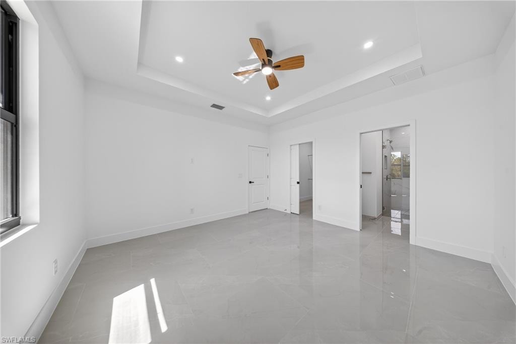 Unfurnished bedroom featuring ceiling fan, a raised ceiling, and recessed lighting