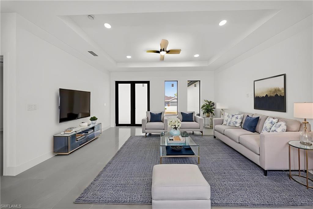 Living area featuring ceiling fan, a tray ceiling, and recessed lighting