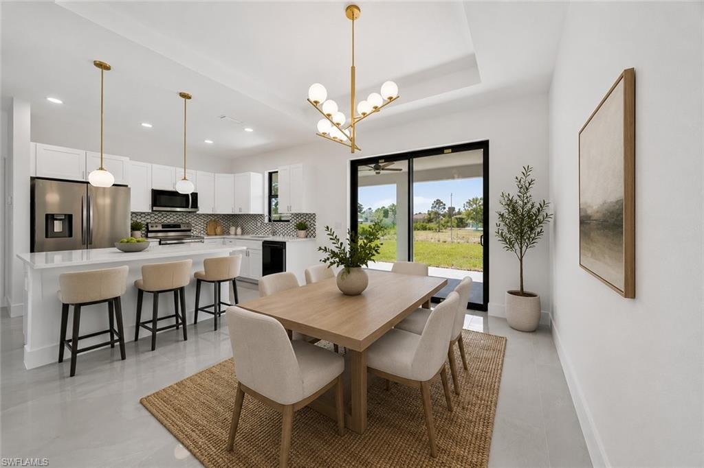 Open-concept kitchen and dining area with white cabinetry, stainless steel appliances, and a mosaic tile backsplash