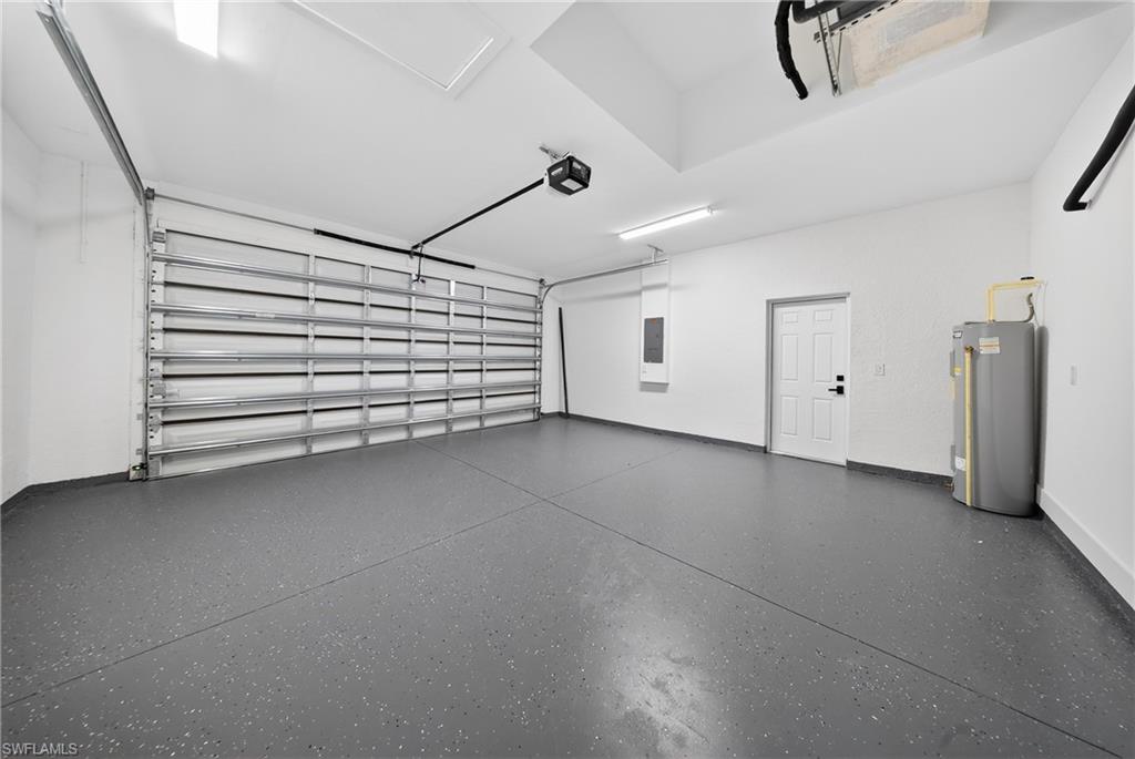 Garage with water heater, electric panel, and a garage door opener