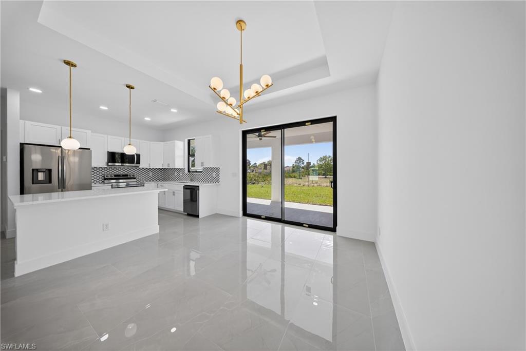 Kitchen featuring white cabinets, a chandelier, stainless steel appliances, backsplash, and a kitchen island