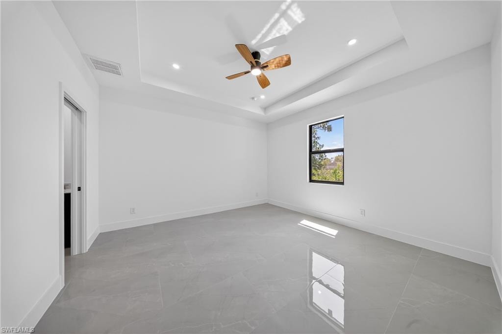Unfurnished room featuring a ceiling fan, recessed lighting, and a tray ceiling