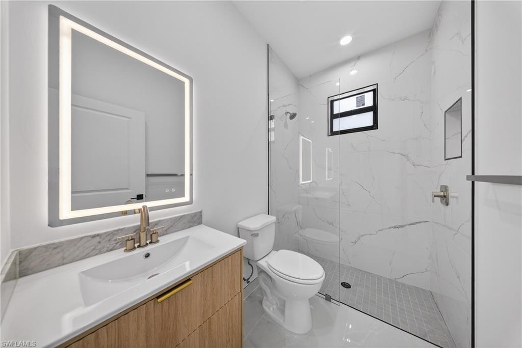 Full bath with vanity, a marble finish shower, and recessed lighting