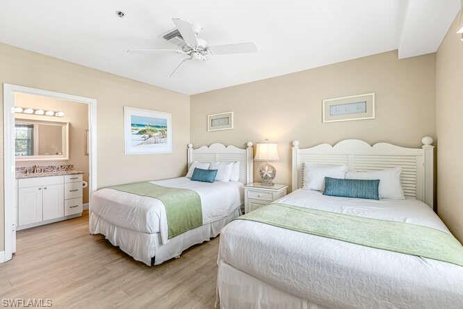 Bedroom with light wood finished floors, ceiling fan, and ensuite bath