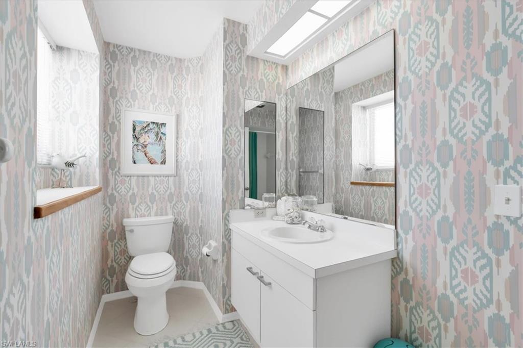 Bathroom featuring wallpapered walls, vanity, and light tile patterned floors