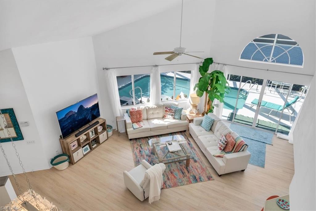 Living room featuring a ceiling fan, wood finished floors, and vaulted ceiling