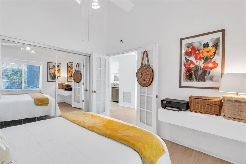 Bedroom with light wood finished floors, a closet, ceiling fan, french doors, and a high ceiling