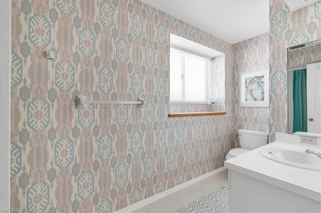 Bathroom with vanity, wallpapered walls, and light tile patterned floors