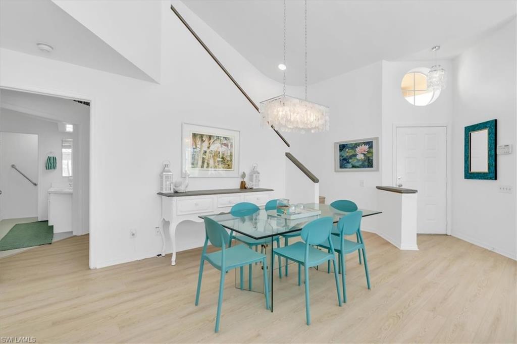 Dining space with light wood-type flooring, a chandelier, and vaulted ceiling