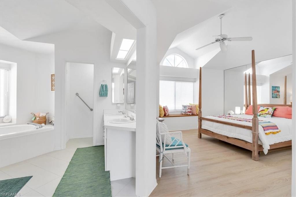 Bedroom with vaulted ceiling, a ceiling fan, and ensuite bathroom