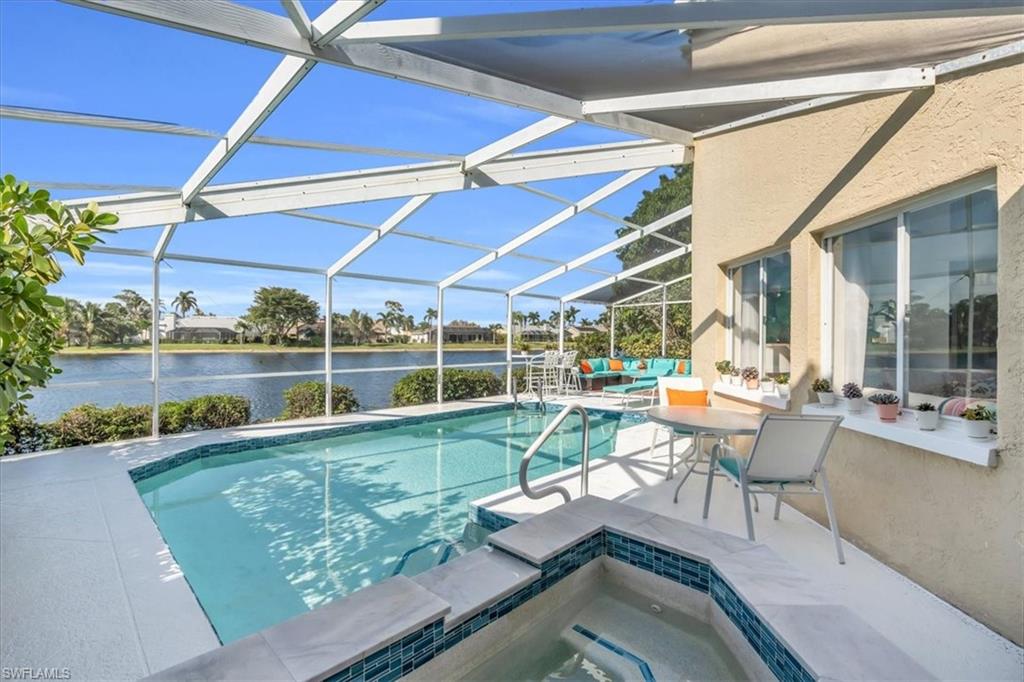 Swimming pool featuring a sunroom, a patio area, glass enclosure, a water view, and an in-ground hot tub