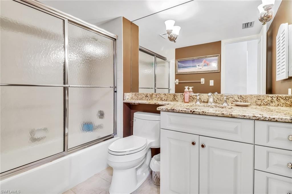 Bathroom featuring vanity, shower / bath combination with glass door, and light tile patterned floors