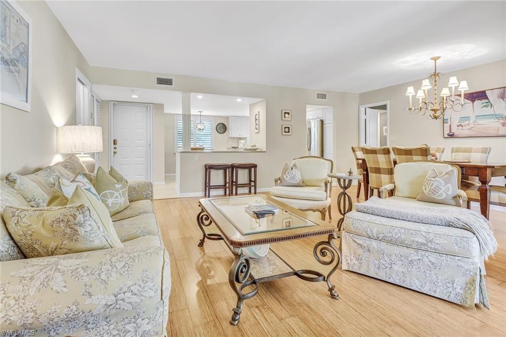 Living room with light wood-style flooring and hanging lights