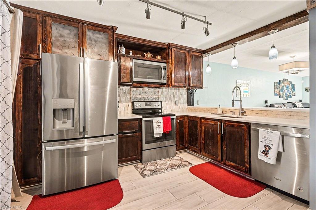 Kitchen with stainless steel appliances, dark wood finish cabinets, wood finish floors, backsplash, and open shelves