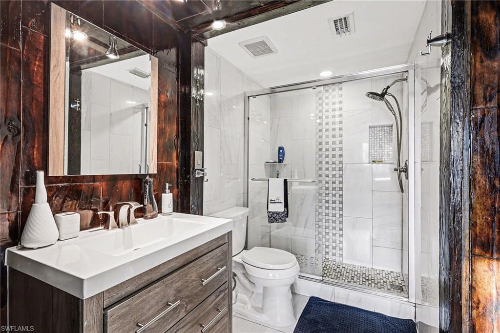 Full bath with tile walls, vanity, and a stall shower