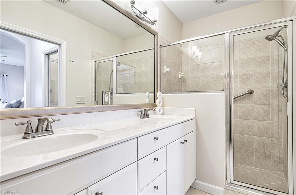 Full bath with double vanity, a stall shower, and connected bathroom