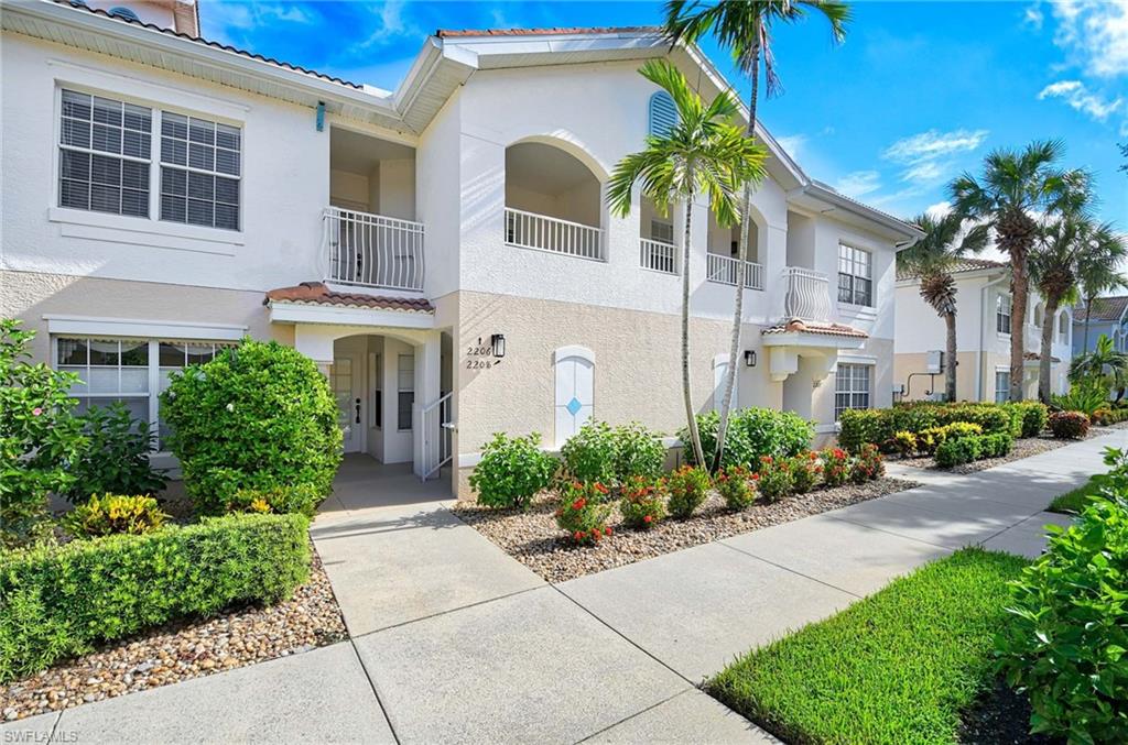 View of front of house with a tile roof, stucco siding, and a balcony