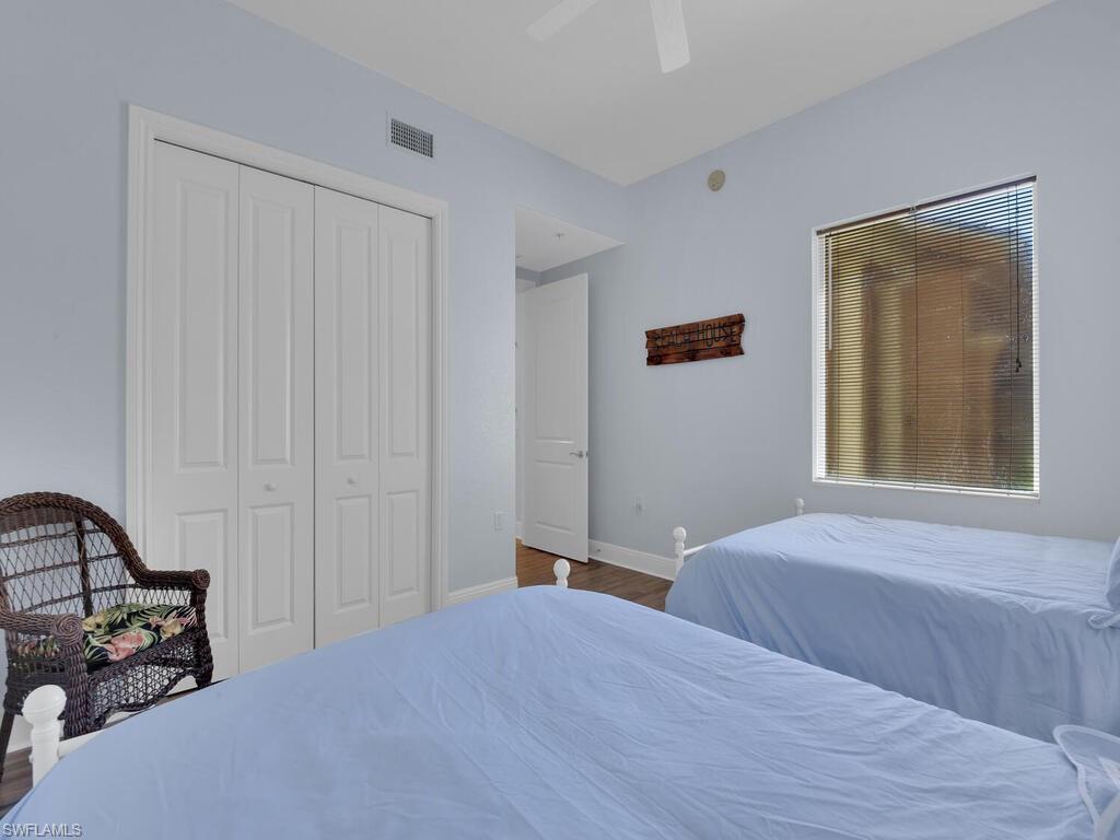 Bedroom with a closet, a ceiling fan, wood finished floors, baseboards, and visible vents