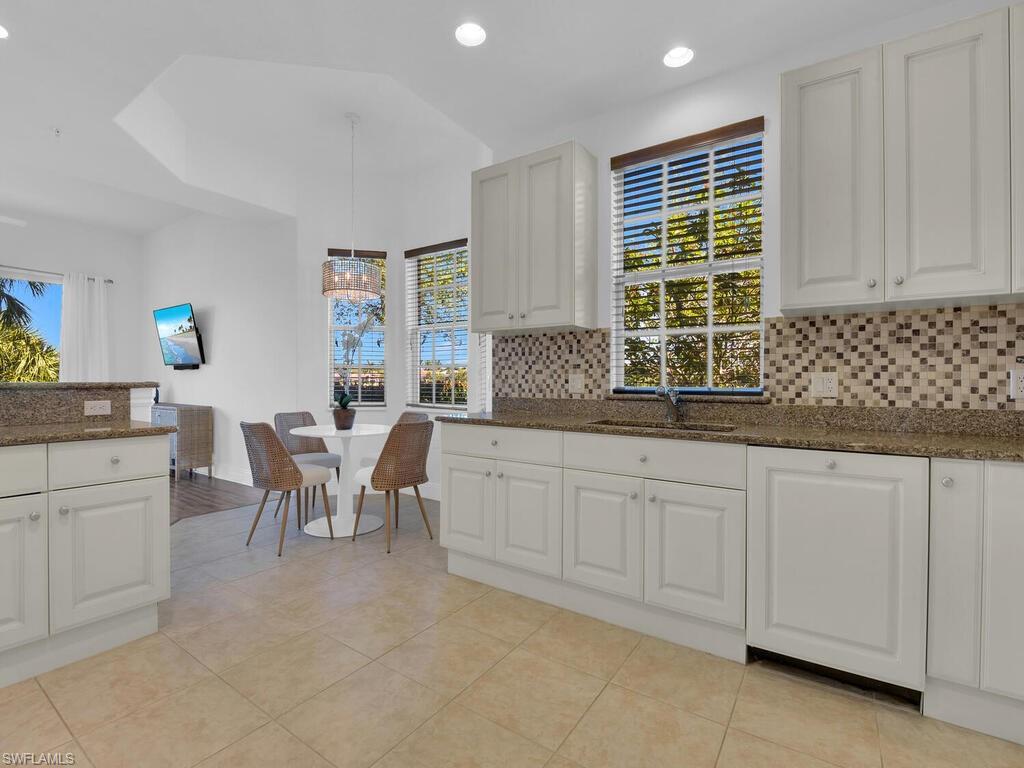 Kitchen with plenty of natural light, tasteful backsplash, dark stone countertops, and a sink