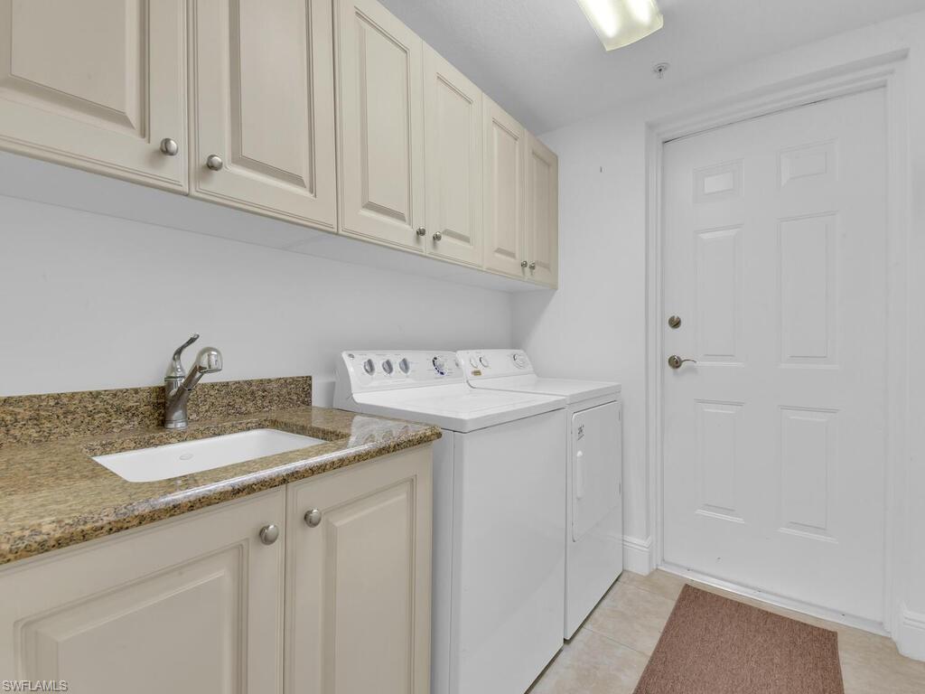 Washroom with light tile patterned floors, a sink, cabinet space, and washing machine and dryer
