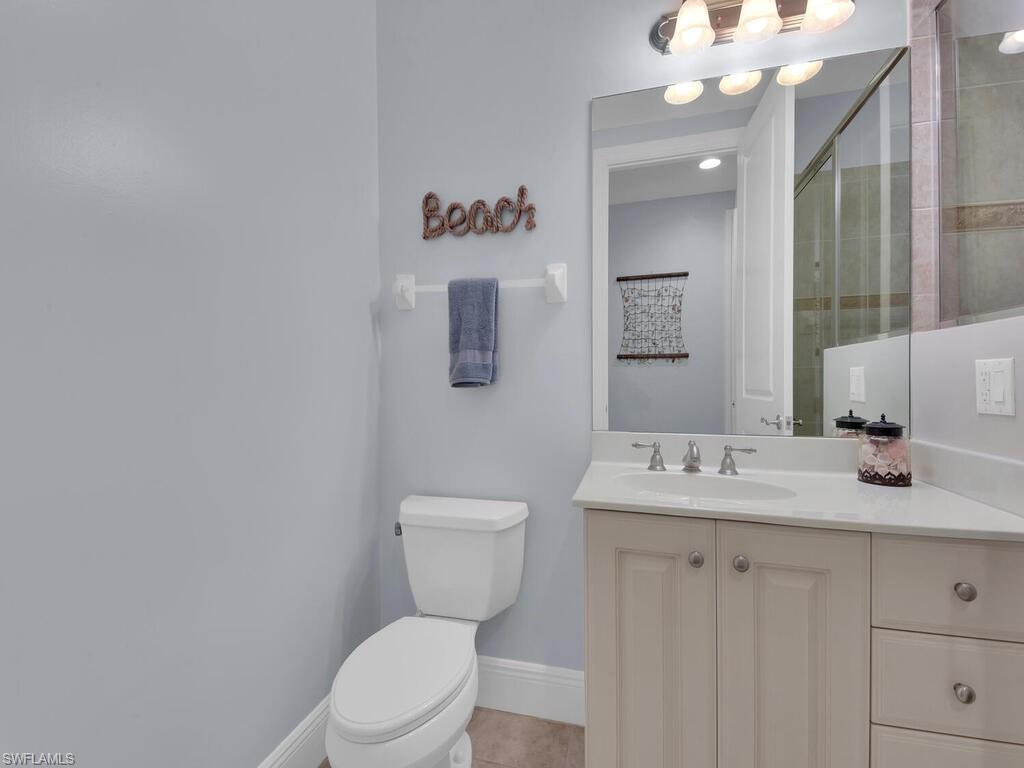 Full bathroom with vanity, a tile shower, toilet, baseboards, and tile patterned floors