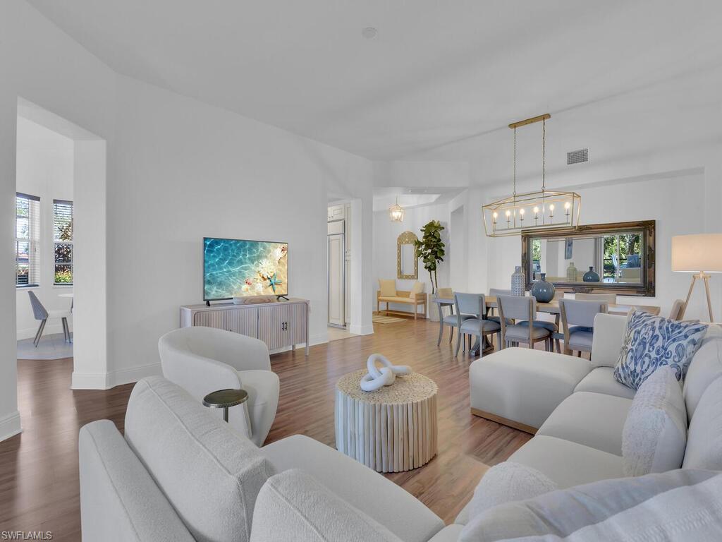 Living area featuring baseboards, visible vents, wood finished floors, and a chandelier