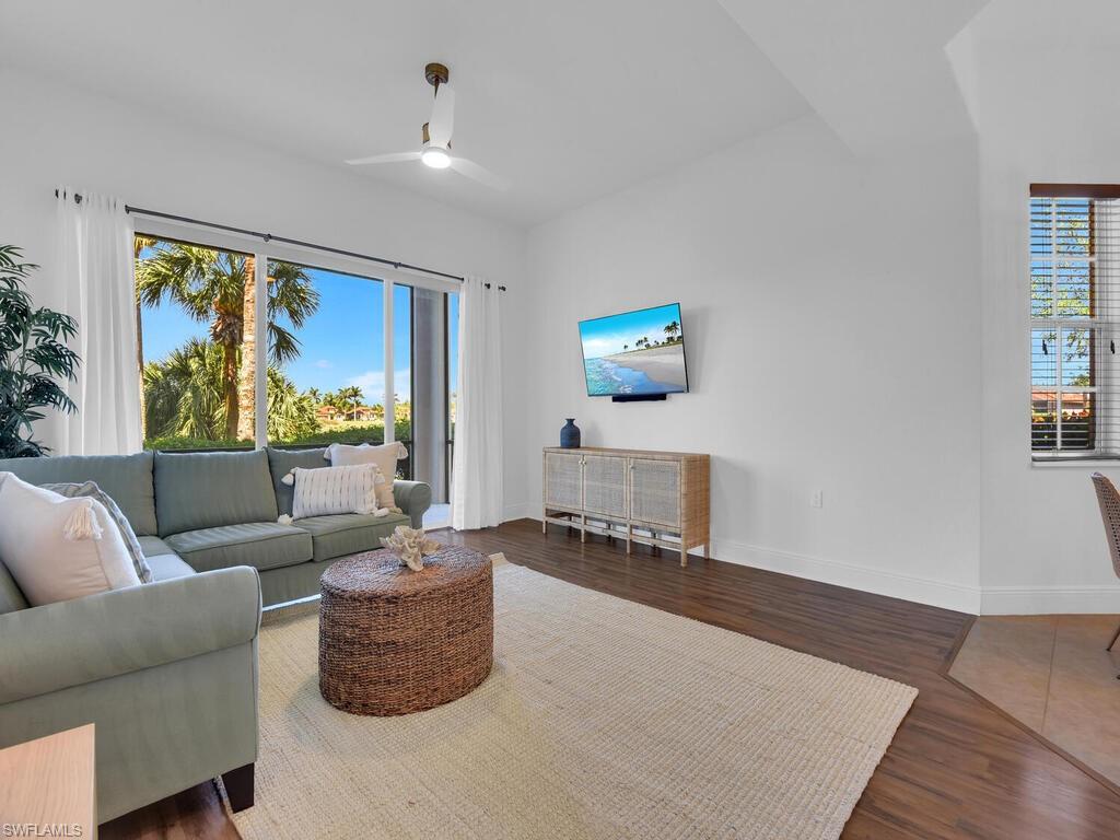 Living area with a healthy amount of sunlight, wood finished floors, baseboards, and a ceiling fan