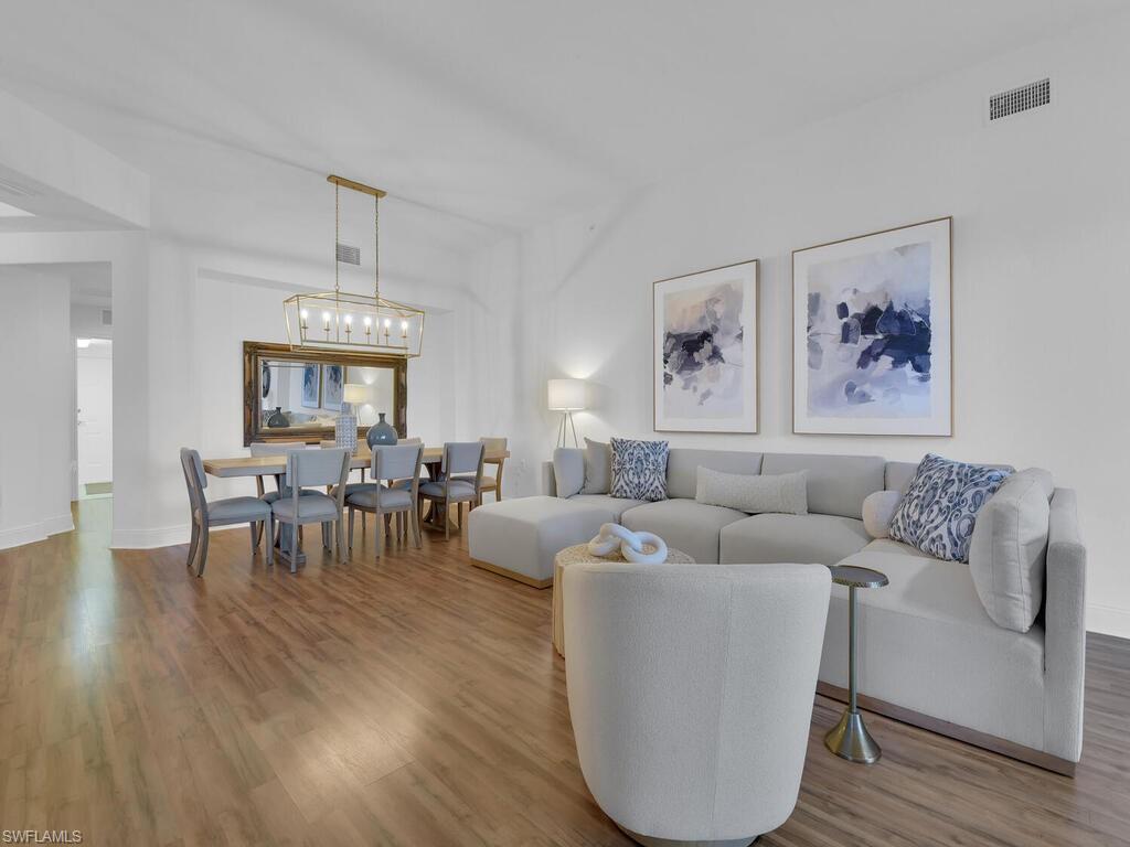 Living area featuring wood finished floors, baseboards, a chandelier, and visible vents