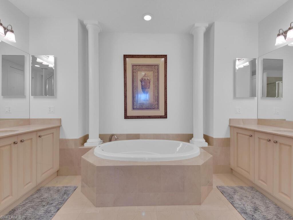 Bathroom featuring a sink, two vanities, a bath, and ornate columns