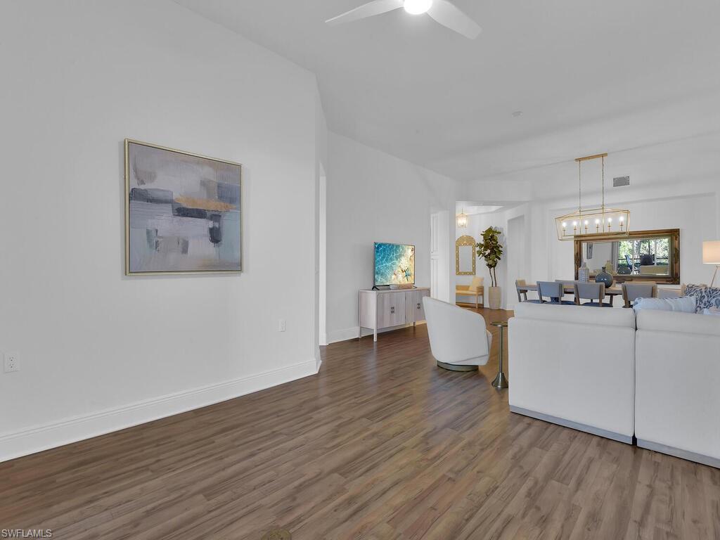 Living area with baseboards, visible vents, wood finished floors, and a ceiling fan