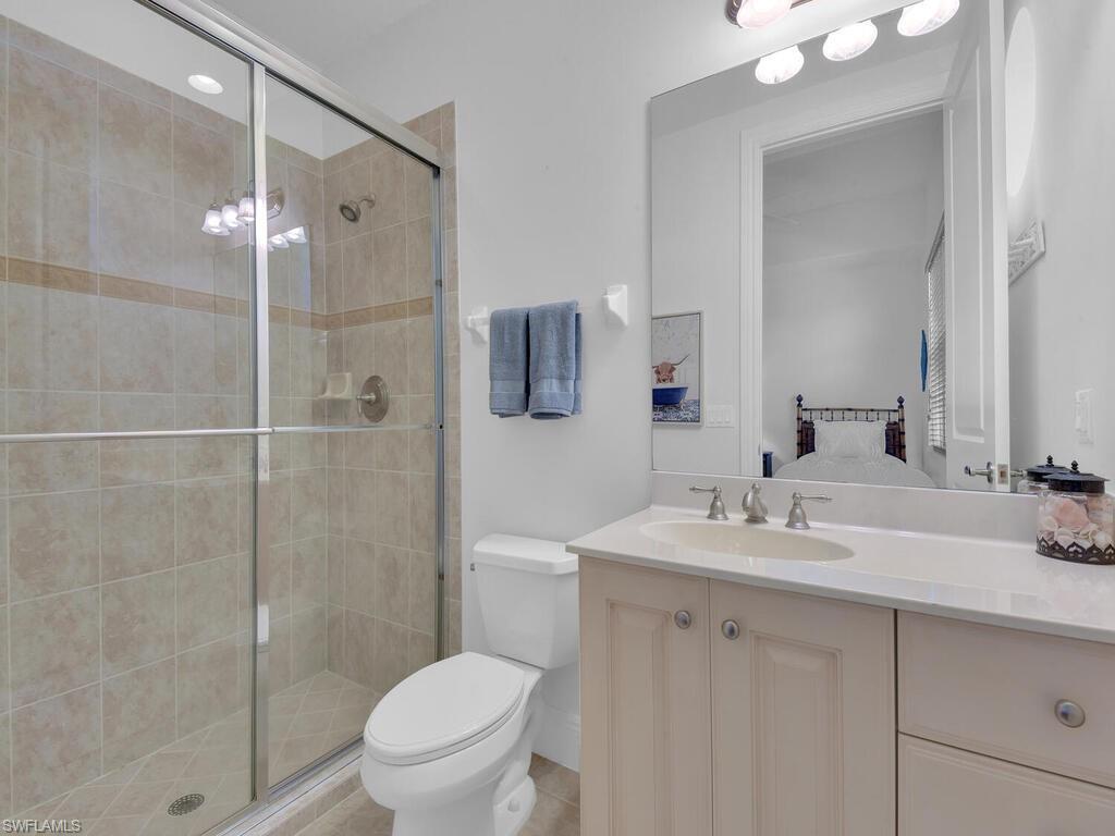 Full bath with toilet, a stall shower, and vanity