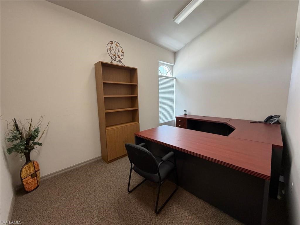 Office space with lofted ceiling and light colored carpet