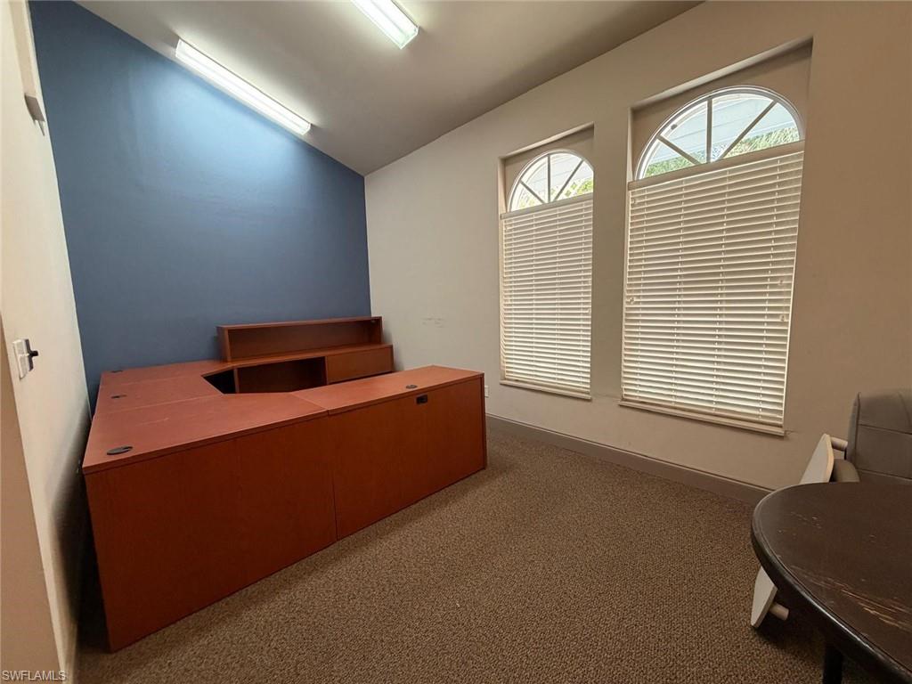Home office featuring lofted ceiling and dark carpet