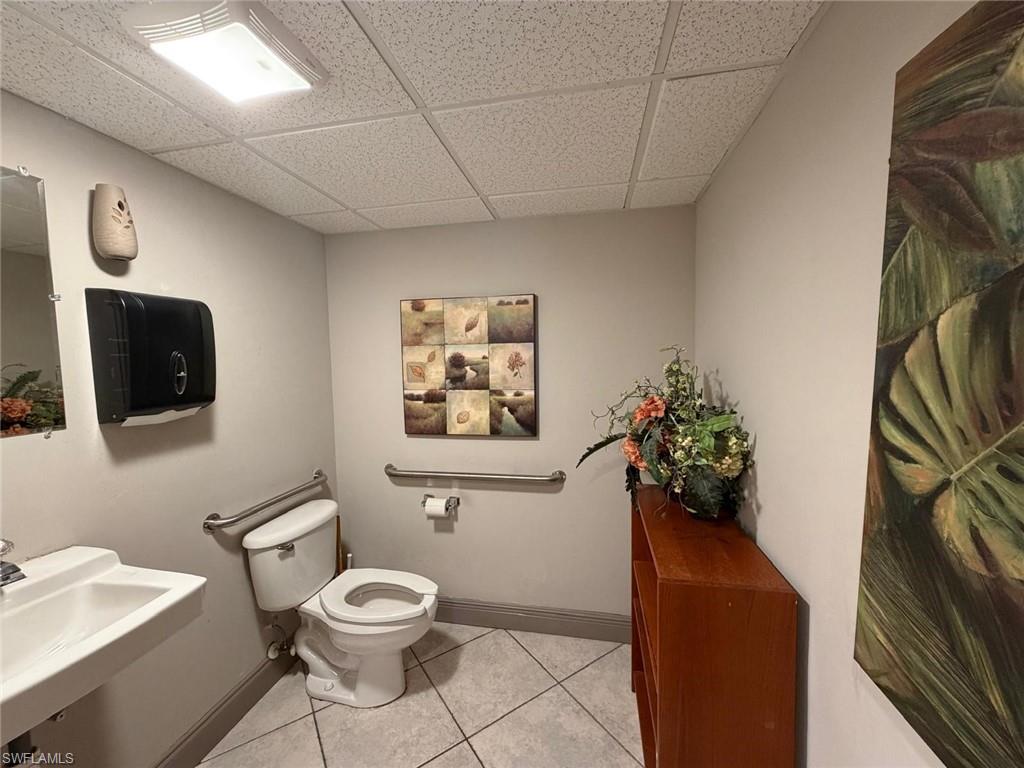 Half bathroom with a drop ceiling and light tile patterned floors