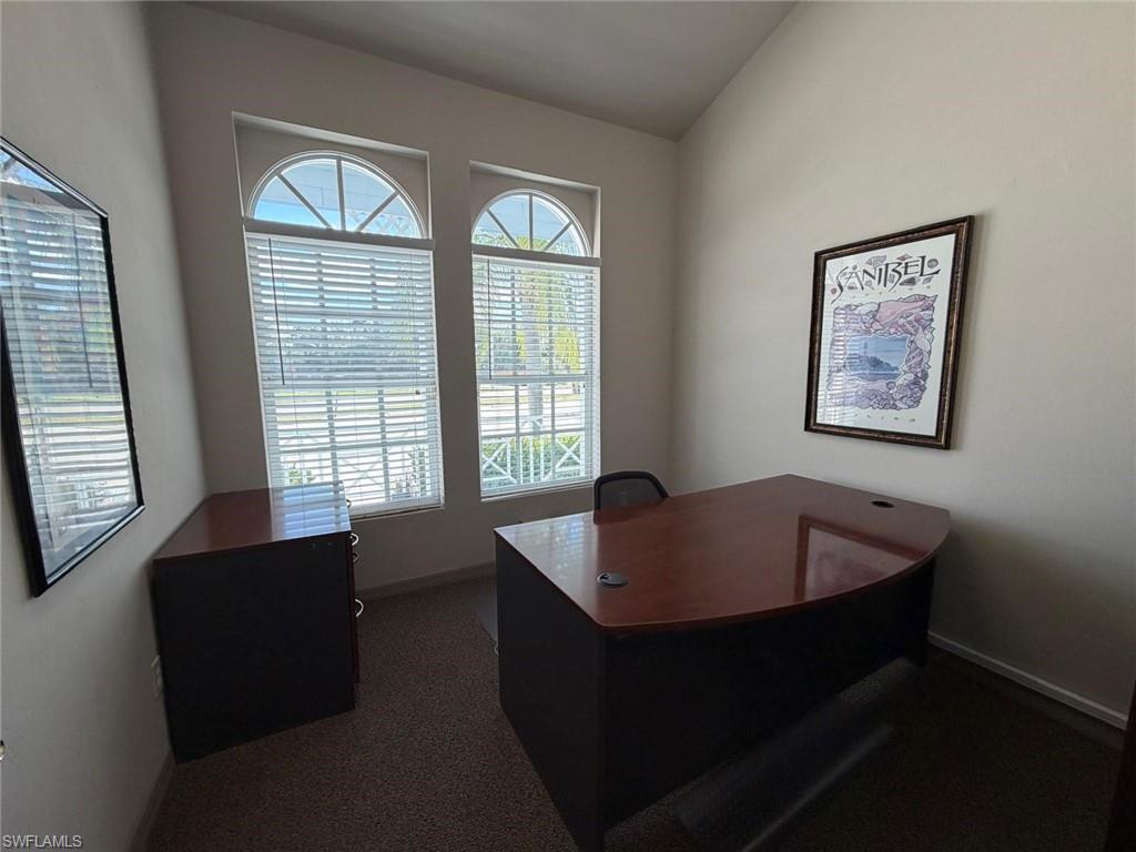 Office area with dark carpet and vaulted ceiling